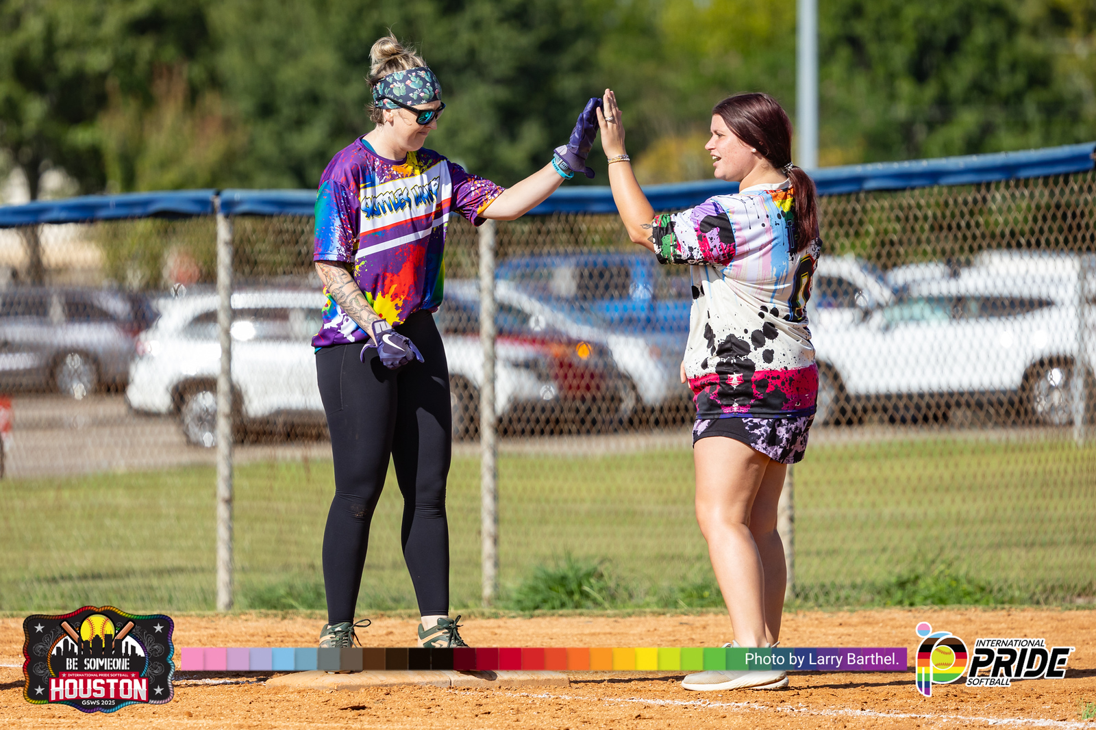 Two adult teammates celebrating together on the softball field at sunset